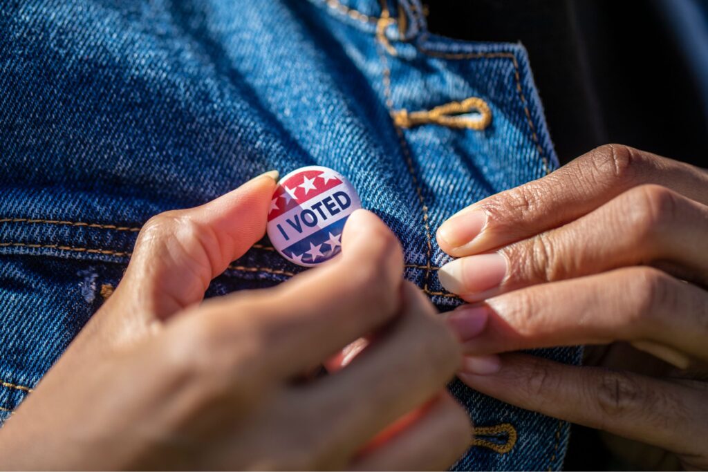 hands putting on an "I voted" pin